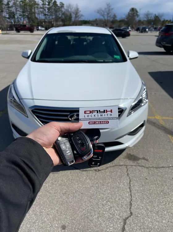 Hyundai keys and an Onyx card held up at a white Hyundai Sonata
