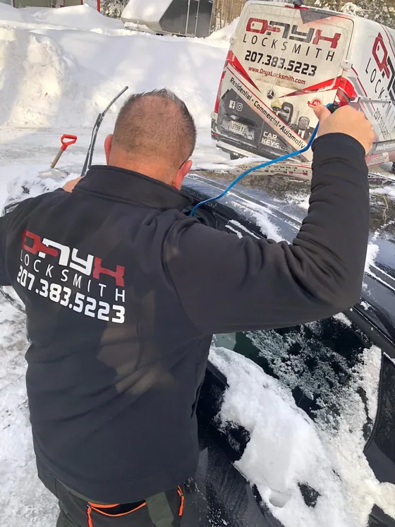 An Onyx technician opening a snowbound car with a long-reach tool